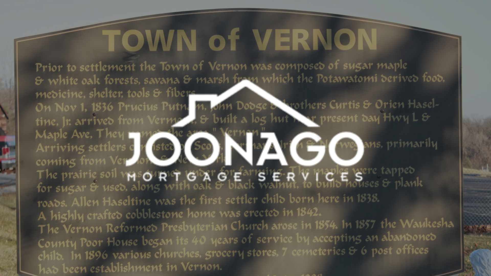 Bronze plaque with text about the Town of Vernon history, overlaid by a logo for Joonago Mortgage Services.