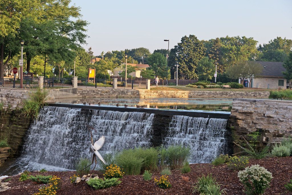 A waterfall is surrounded by trees and flowers in a park.