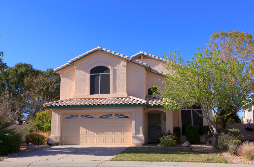 A large arizona house with a large garage and a blue sky in the background.