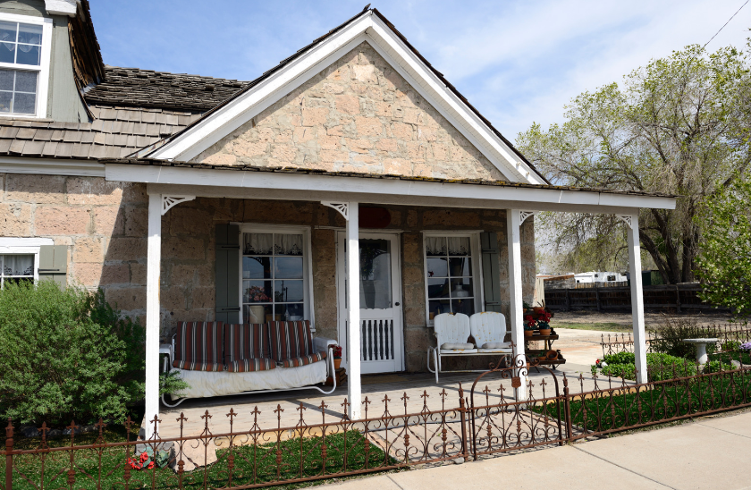 A stone house with a porch and a bench on it