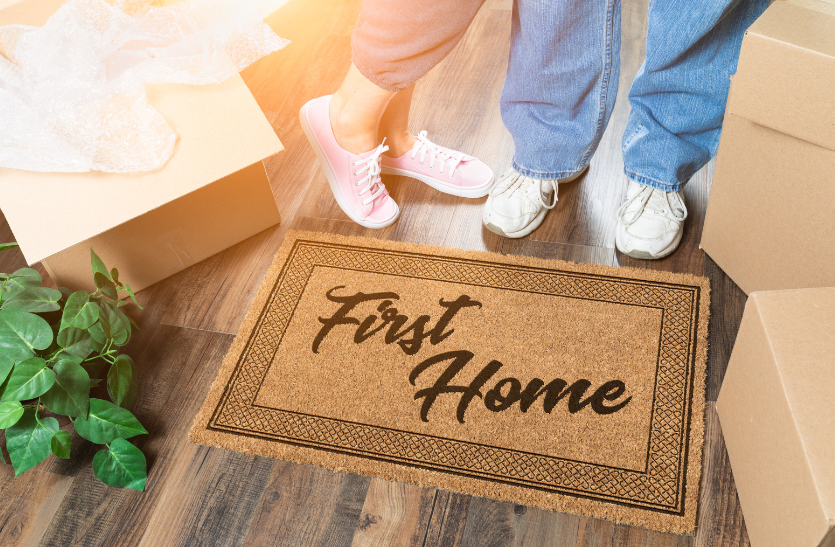 A couple is standing next to a first home doormat.