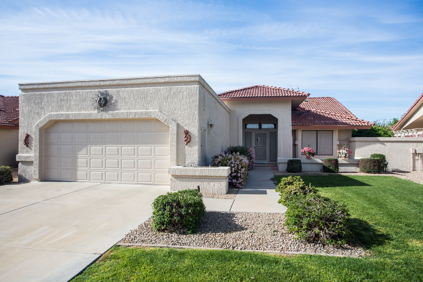 A white house with a large garage and a lush green lawn.