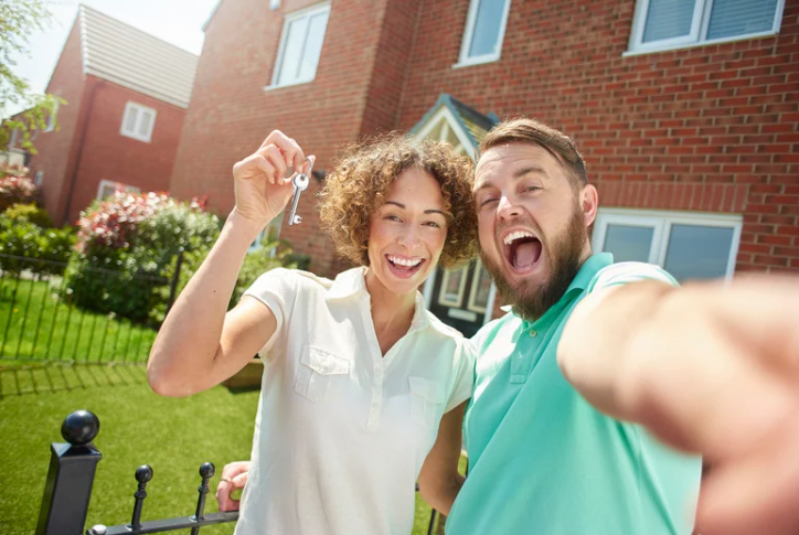 A man and a woman are holding the keys to their new house.