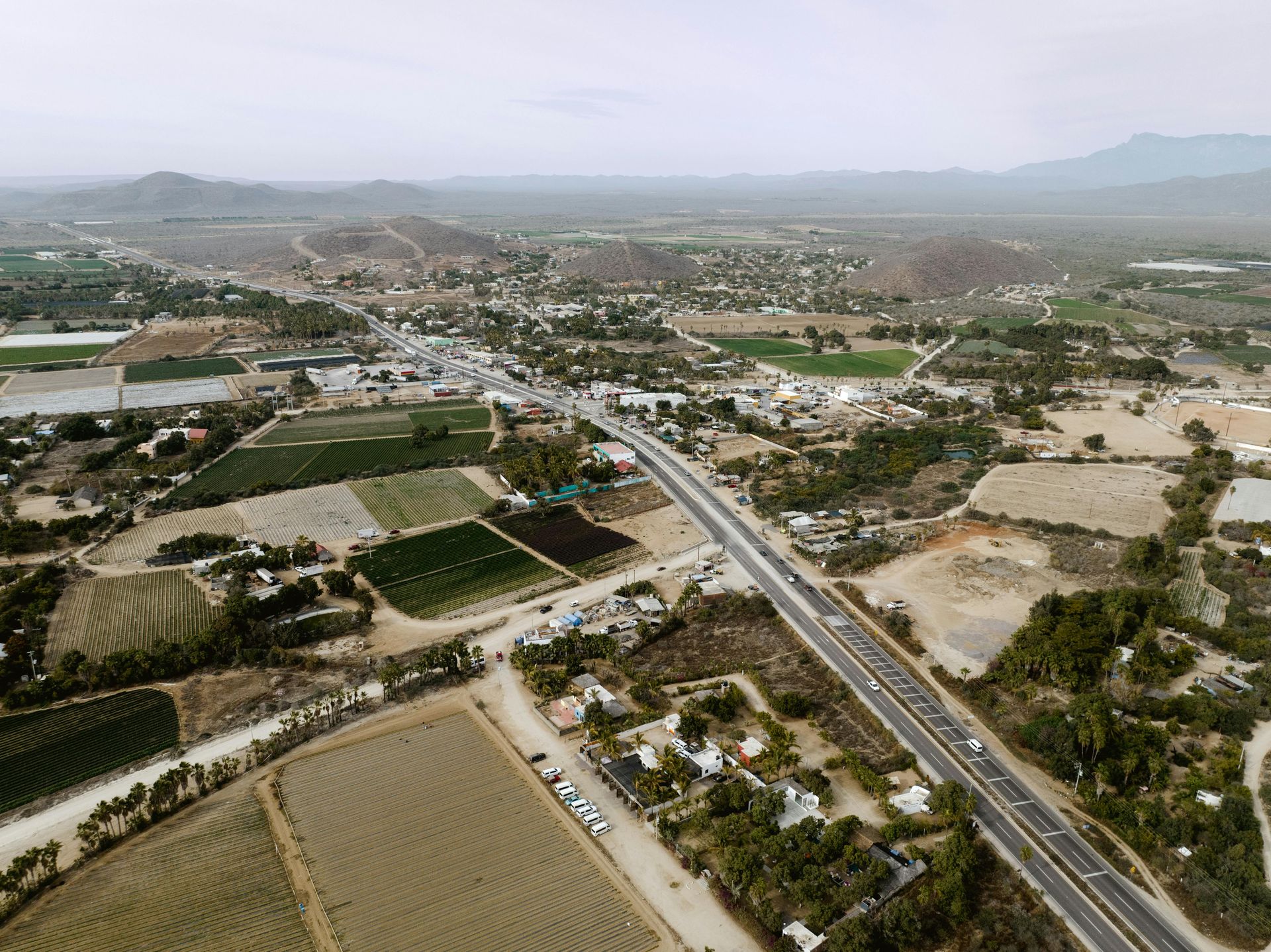 An aerial view of a highway surrounded by fields and trees.