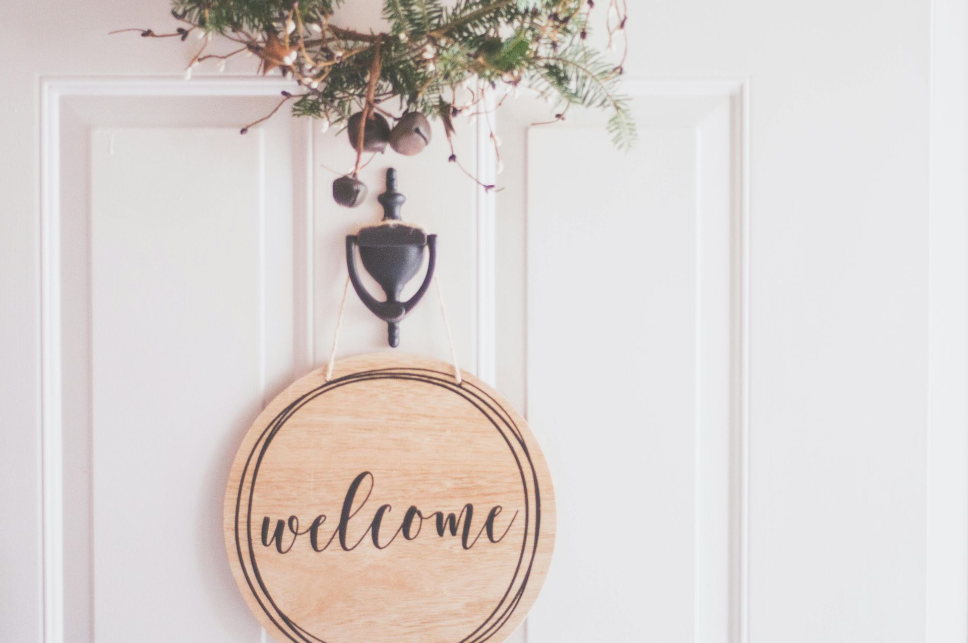 A welcome sign is hanging on a white door.