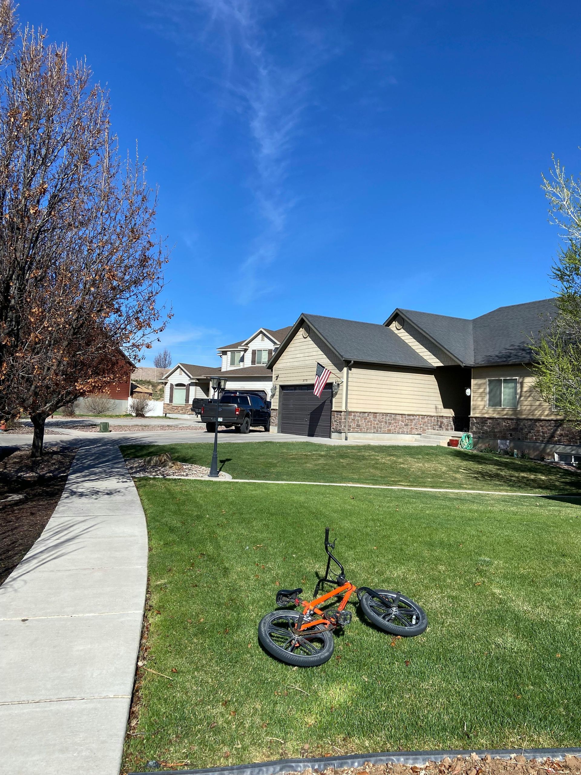 A bicycle is parked in the grass in front of a house.