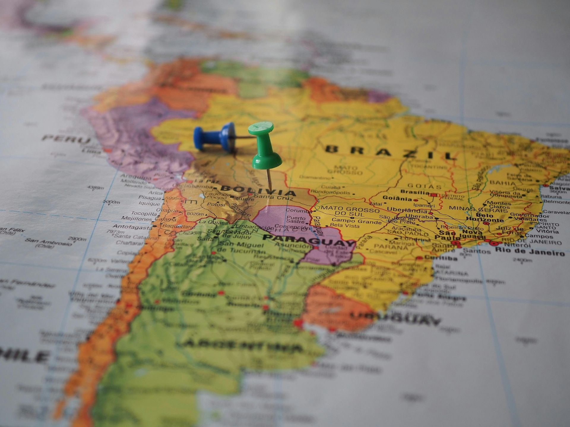 Two pushpins on a colorful map of South America, marking locations near Brazil and Peru