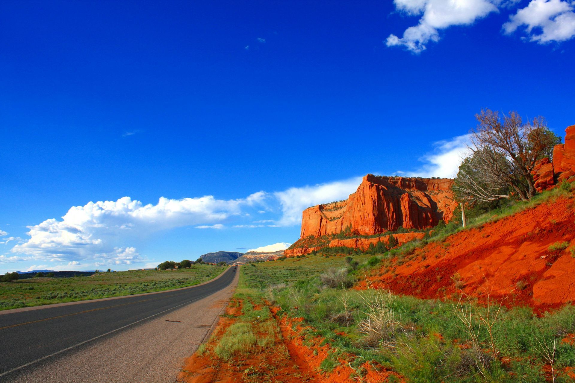 A road with a mountain in the background and a blue sky