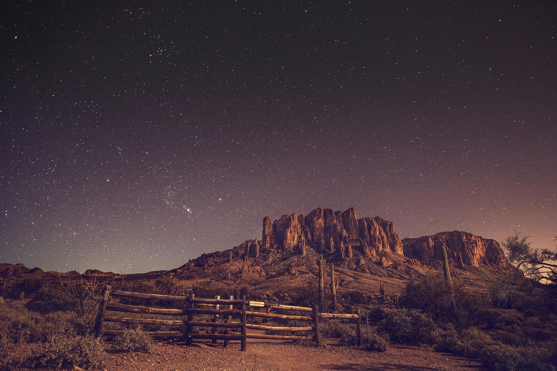 A fence in the desert at night with a mountain in the background