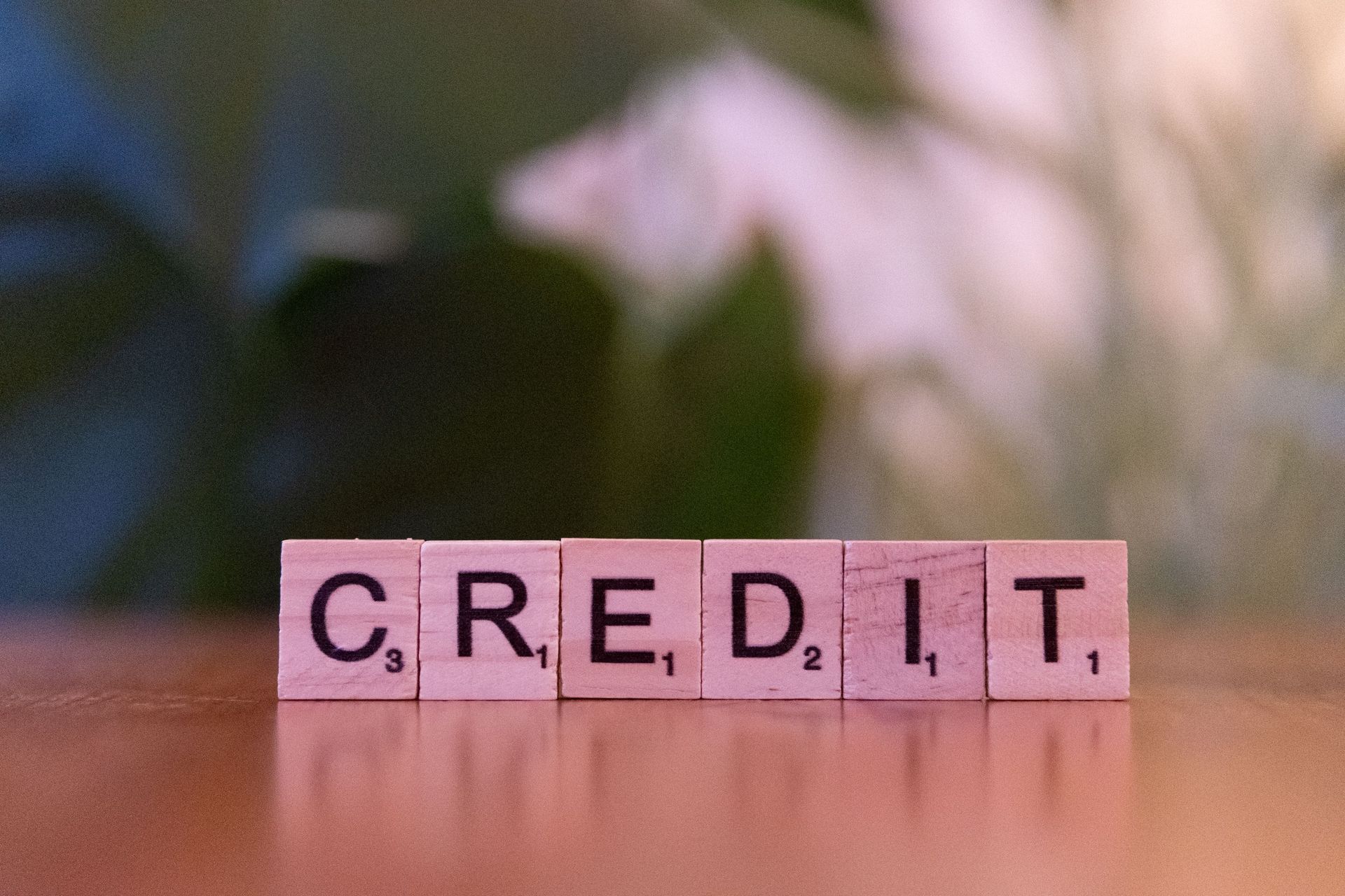 Scrabble tiles spelling “CREDIT” on a wooden surface with a blurred background