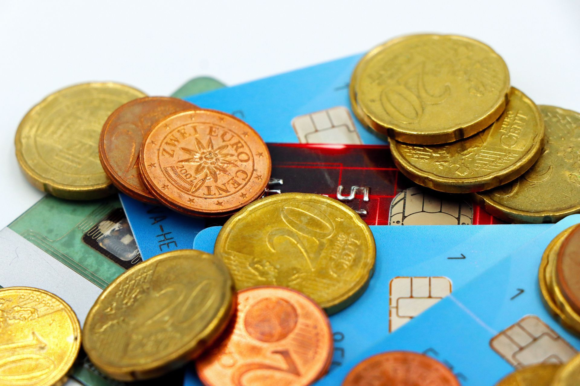 Coins scattered on colorful credit cards, showing cashless payment and finance concept