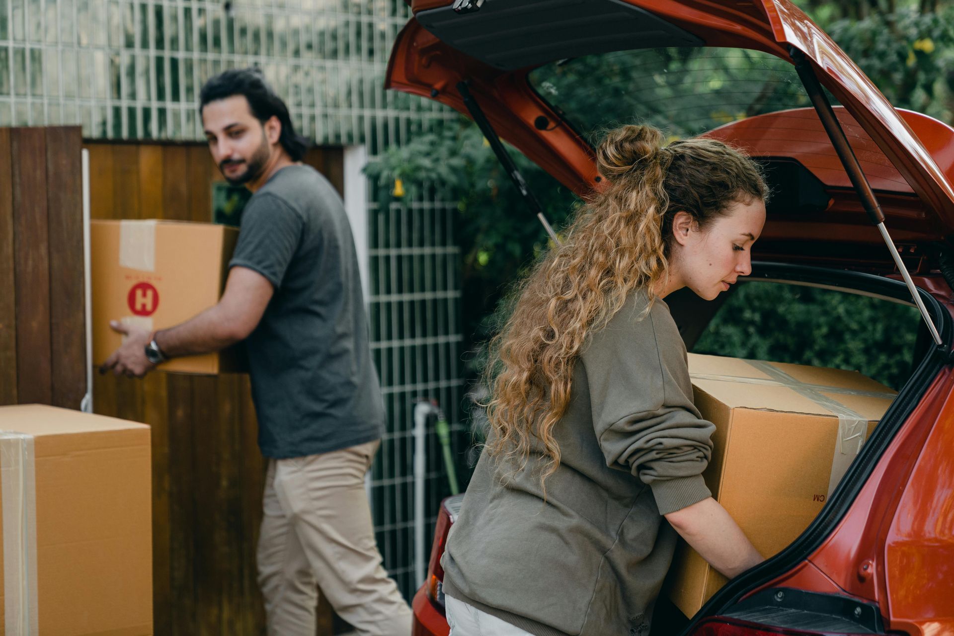 A man and a woman are loading boxes into the back of a car.