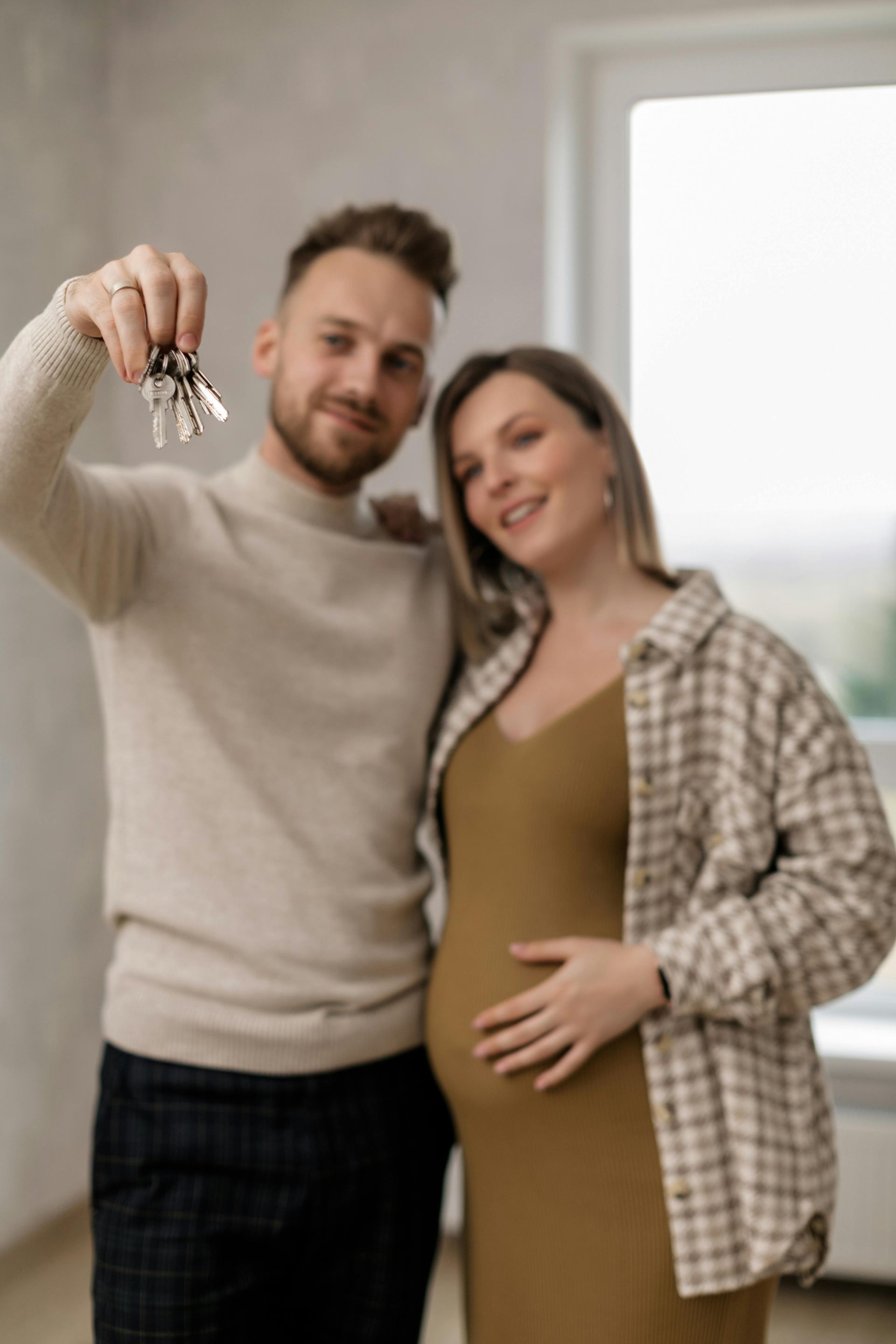 A man is holding a bunch of keys next to a pregnant woman.