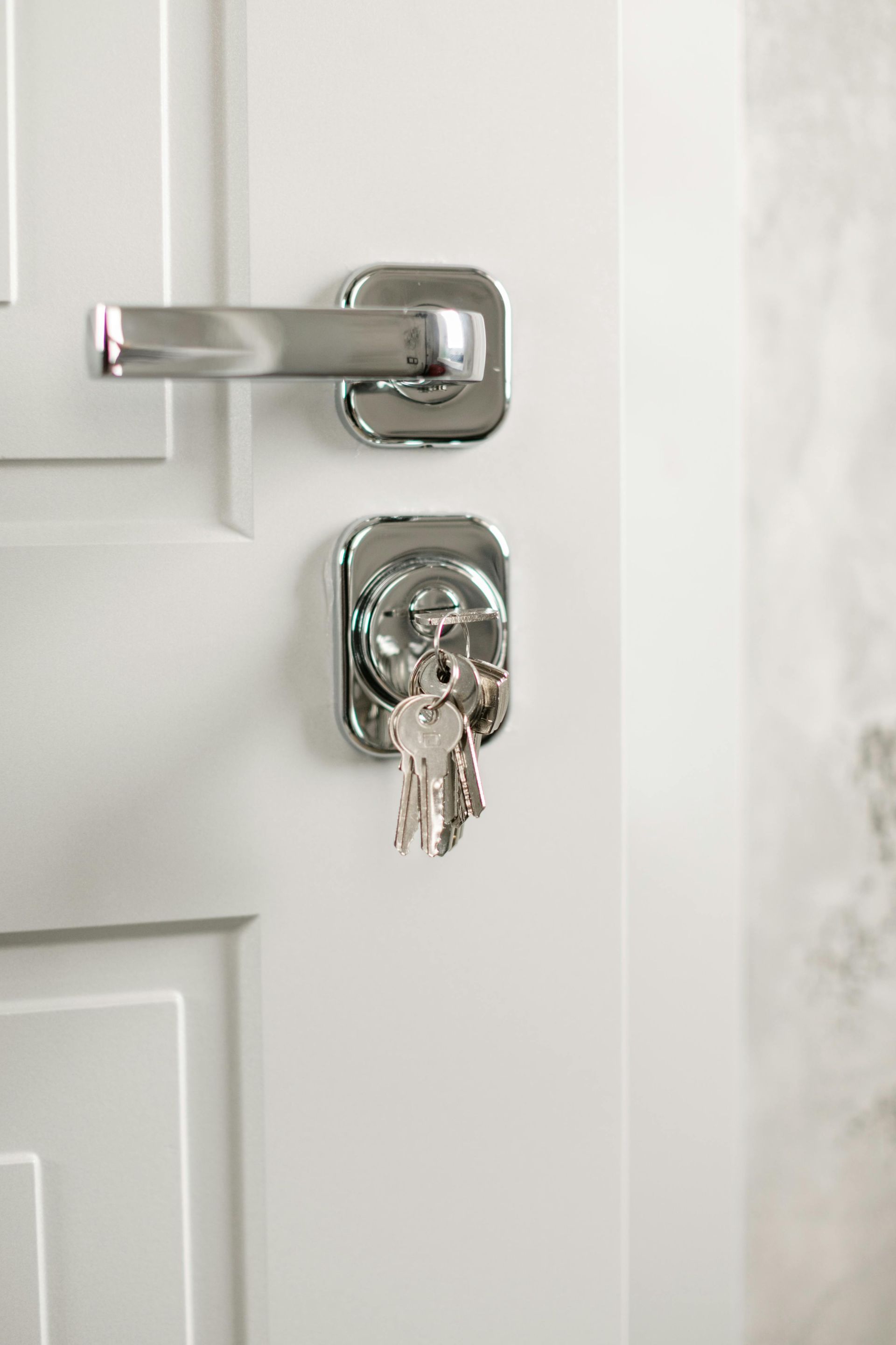 House door with a silver latch lock and keys inserted in the deadbolt