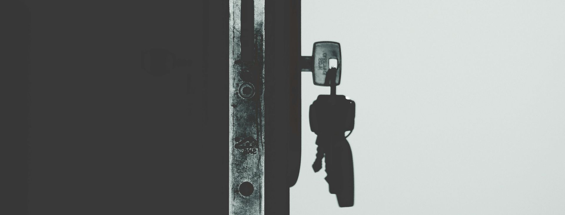 A black and white photo of a key in a door lock.