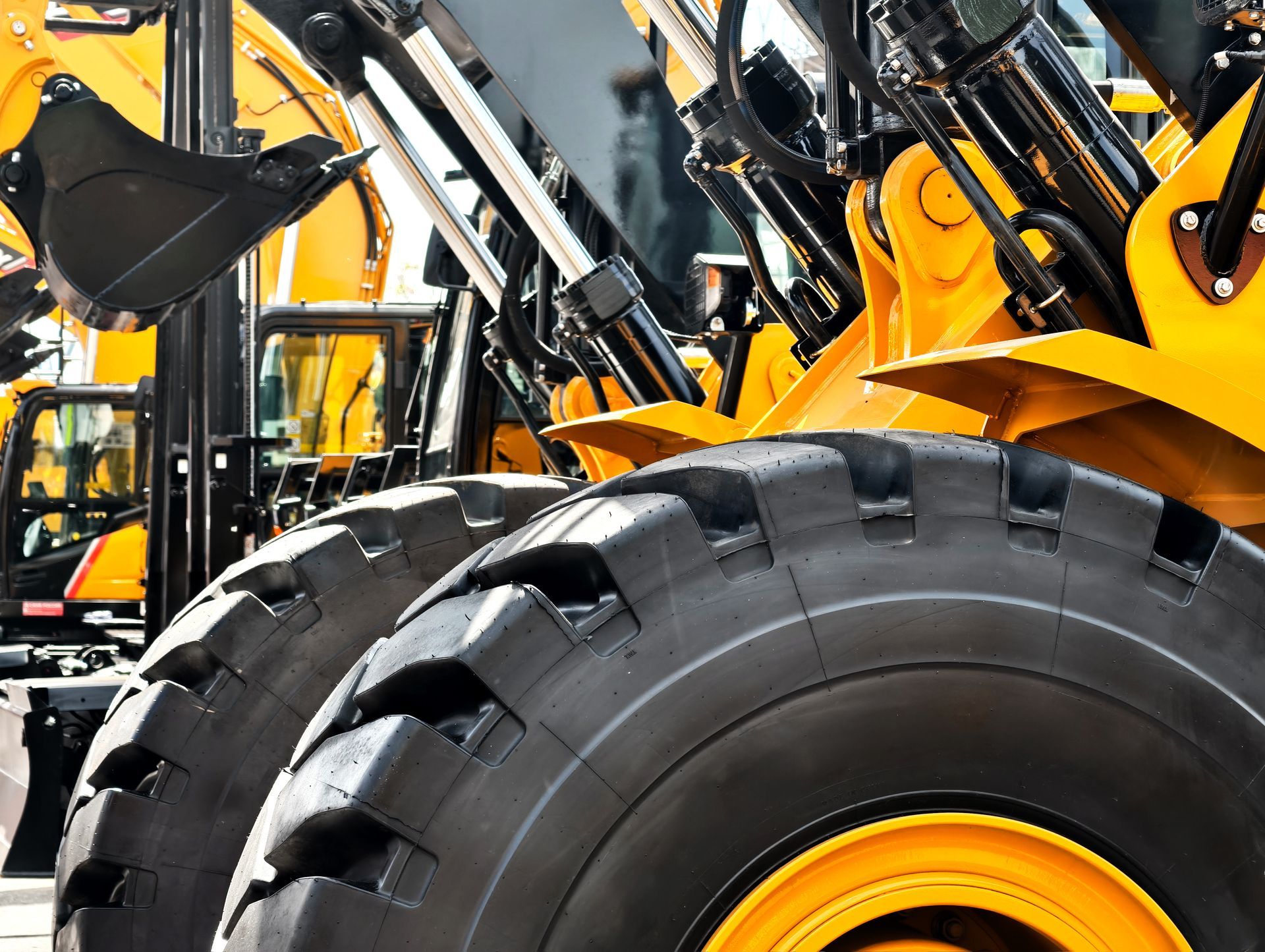 A close-up view of the massive yellow tires and hydraulic machinery of industrial construction vehicles.