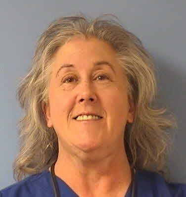 Smiling woman with gray hair against a plain blue background