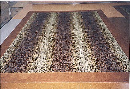 Leopard print carpet with a brown border on a wooden floor.
