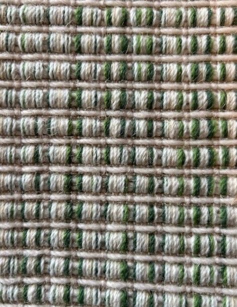 Close-up of woven fabric with alternating horizontal stripes in shades of green and beige.