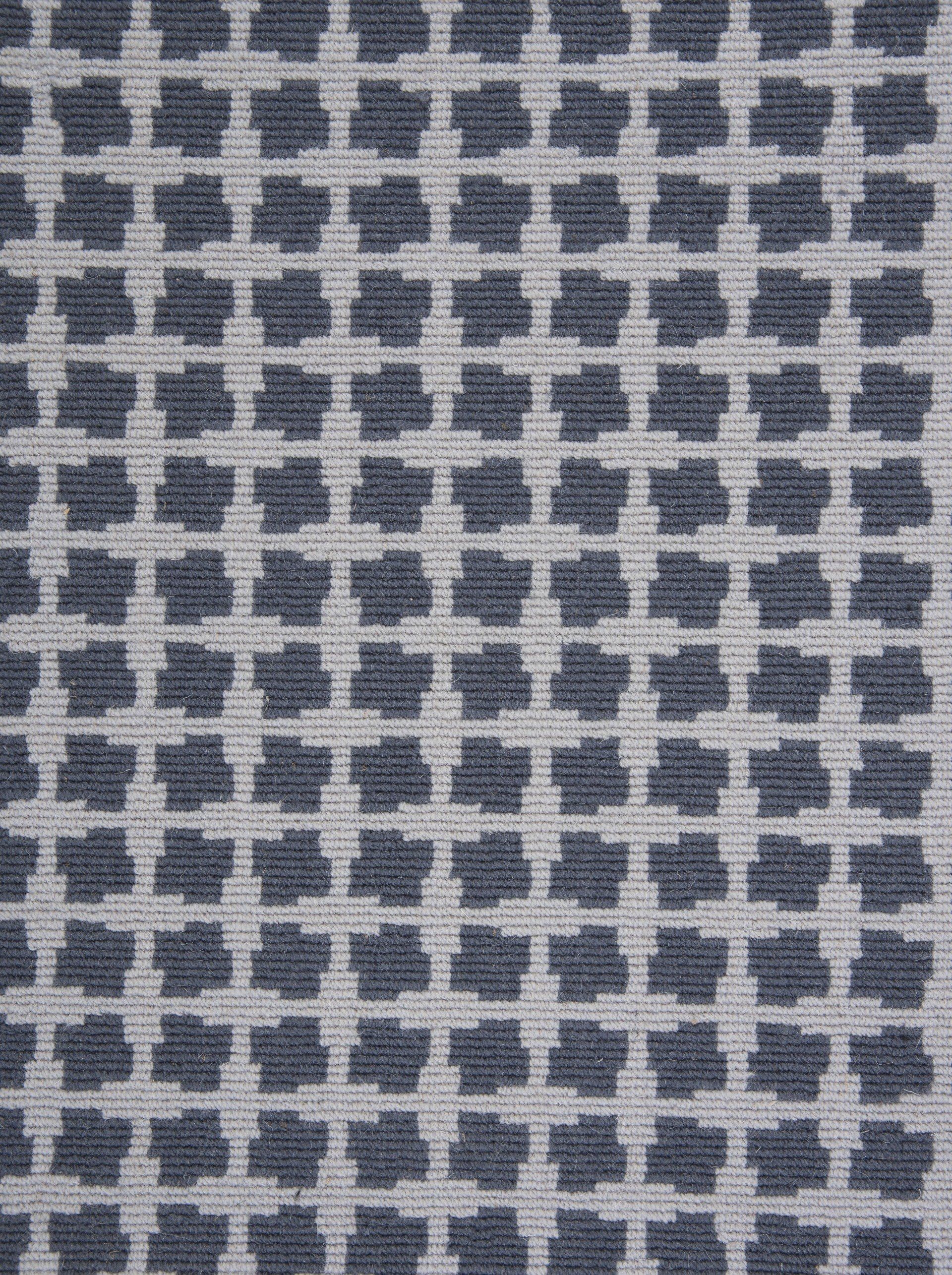Gray and white patterned textile; checkered design of dark gray shapes.