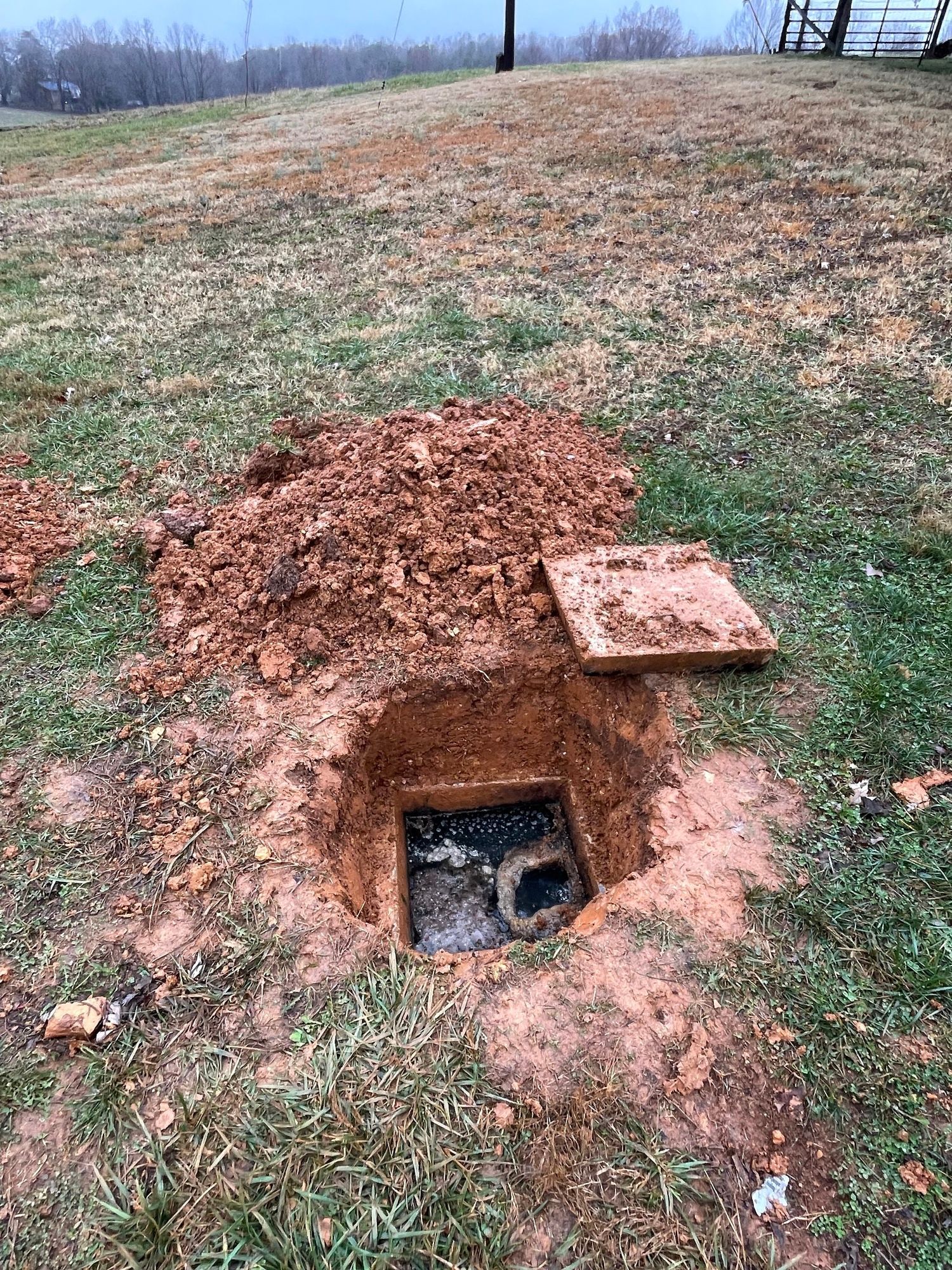 A hole in the ground with a drain in it.