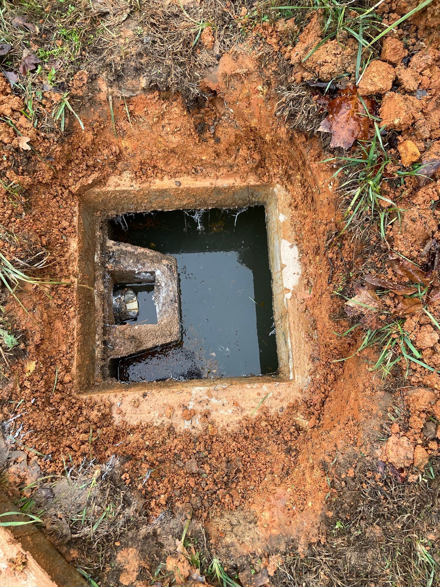 A square hole in the ground with water in it.