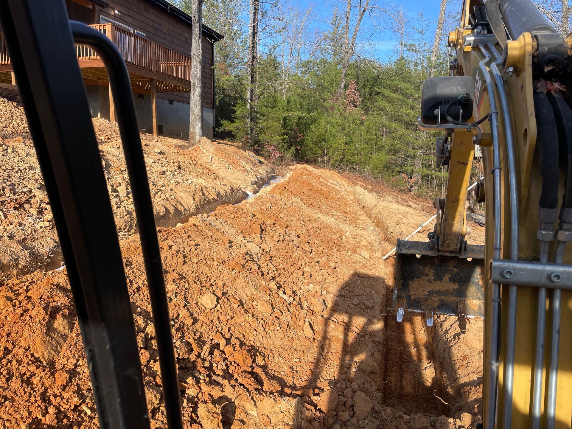 A bulldozer is digging a hole in the dirt in front of a house.