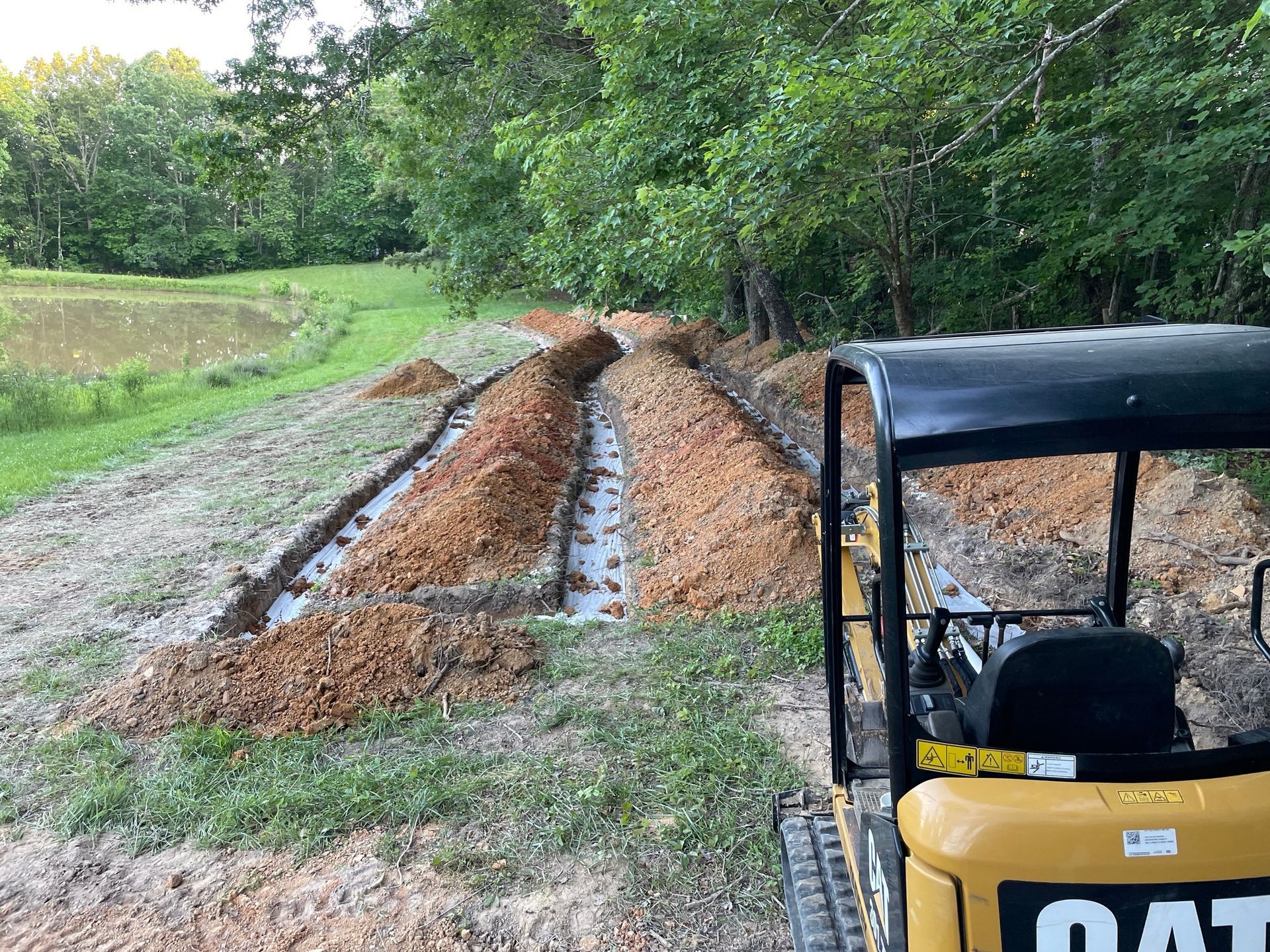 A cat mini excavator is driving down a dirt road.