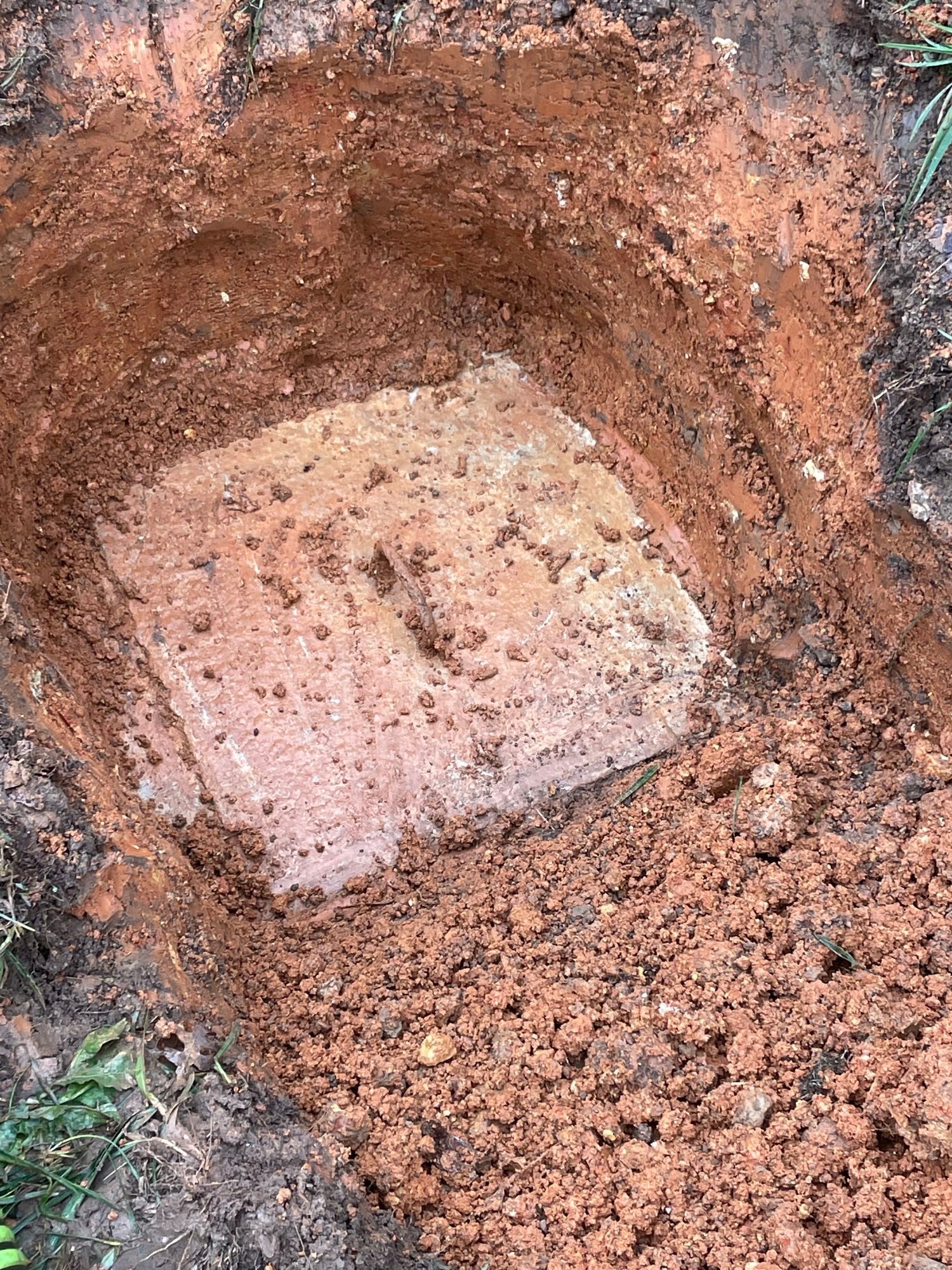 A square piece of wood is sitting in the middle of a pile of dirt.