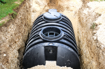 A large black septic tank is sitting in a trench.