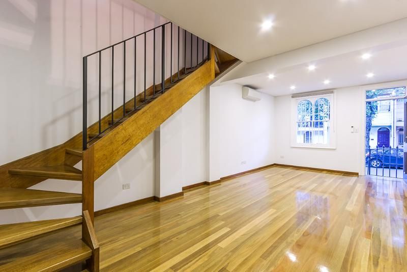 An empty living room with a wooden staircase and hardwood floors.