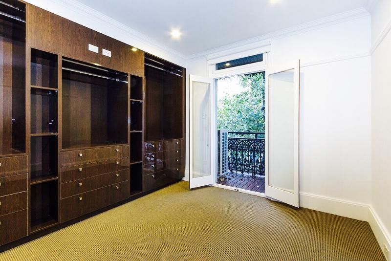 An empty room with a balcony and a large walk in closet.