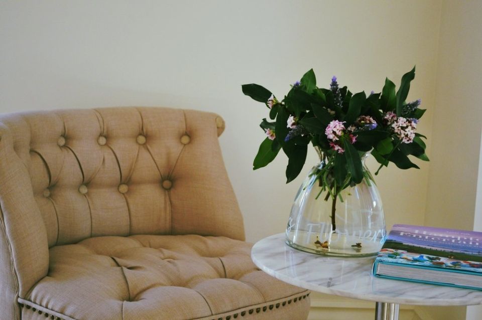 A chair and a table with a vase of flowers on it