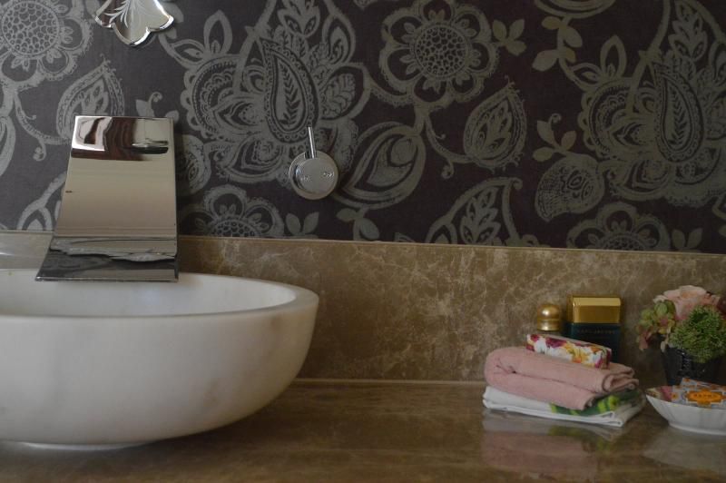 A bathroom sink with a floral wallpaper on the wall.
