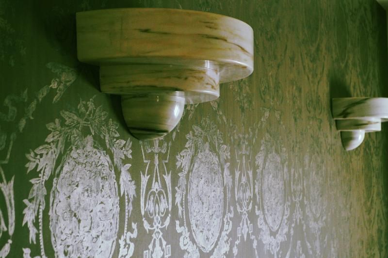 Three wooden shelves are hanging on a wall with a patterned wallpaper.