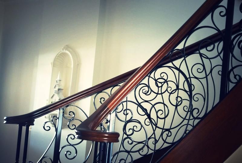 A staircase with a wrought iron railing and a wooden handrail