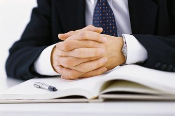 Lawyer hands clasped resting on open book