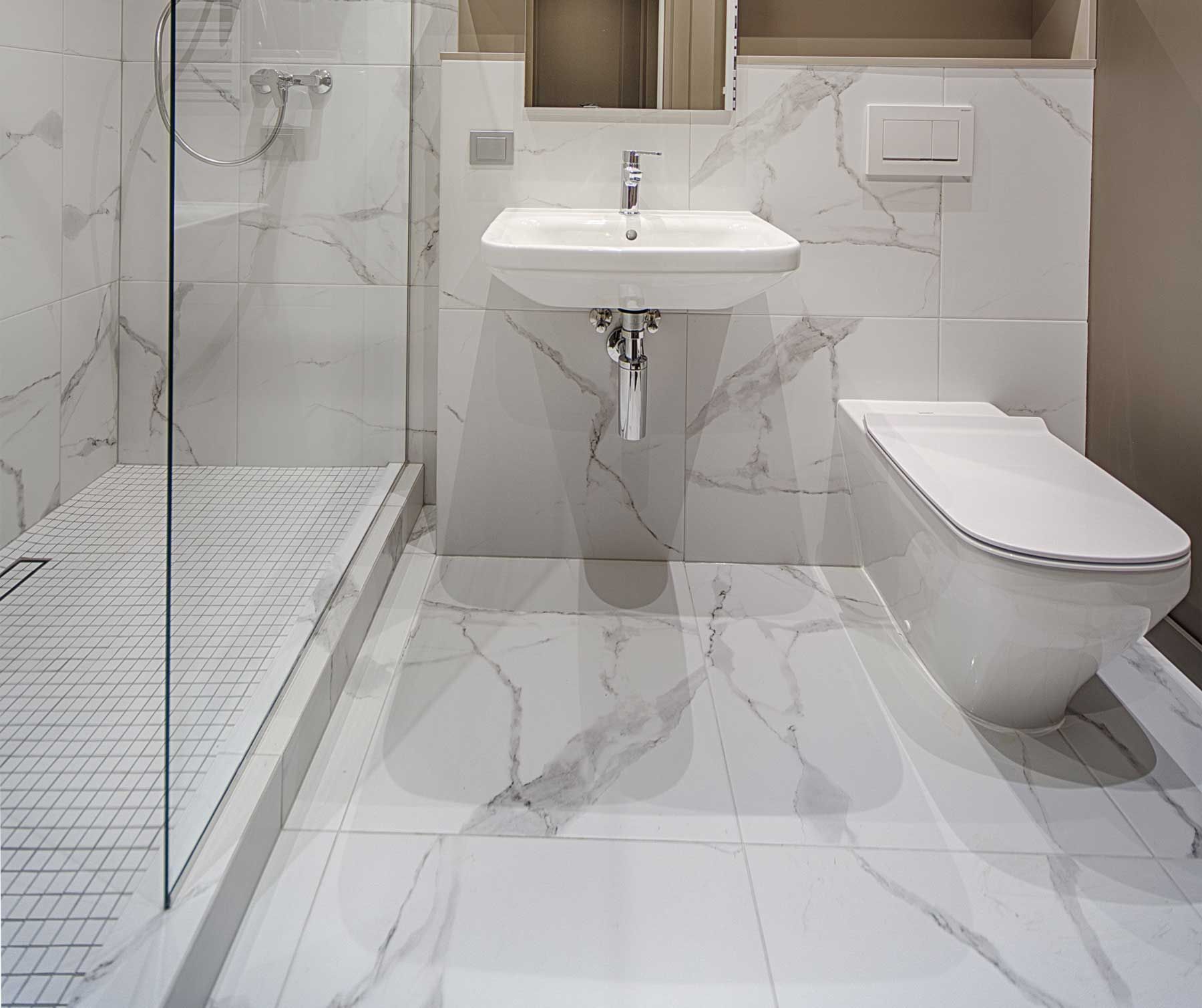 A bathroom with a sink , toilet , shower and mirror.