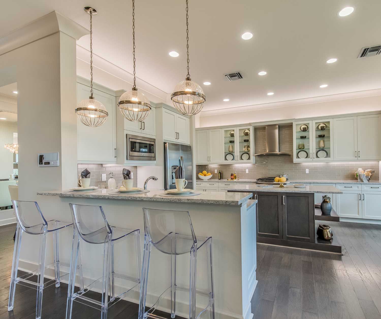 A kitchen with white cabinets and clear stools