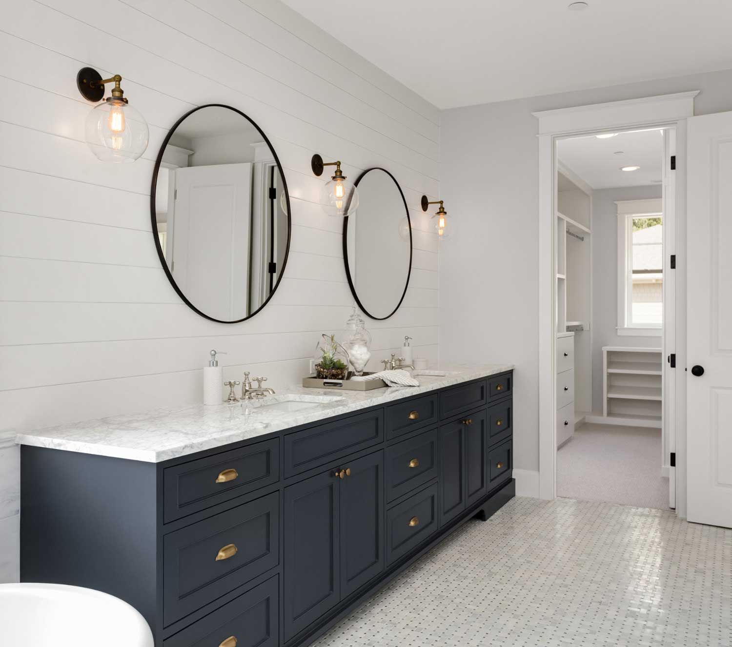 A bathroom with two sinks , two mirrors and a bathtub.