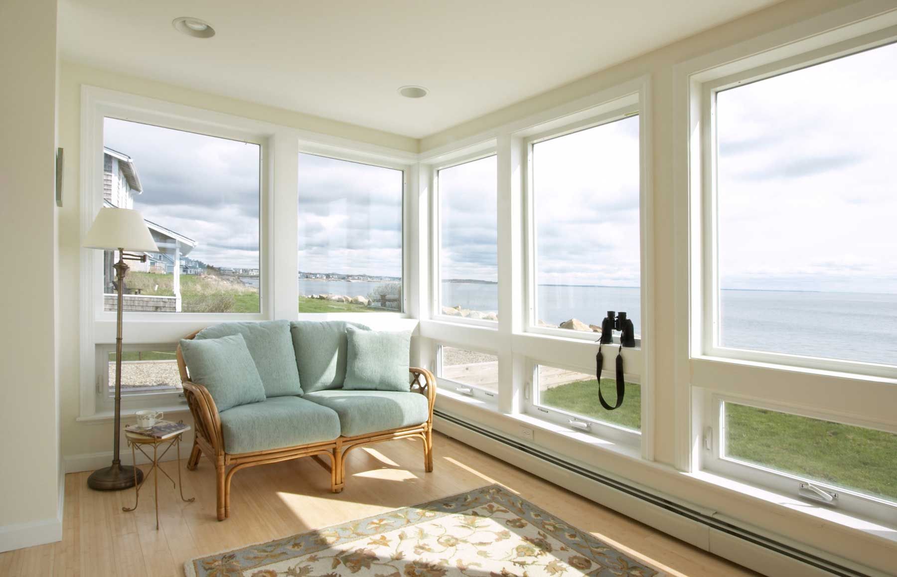 A living room with a couch and lots of windows overlooking the ocean.