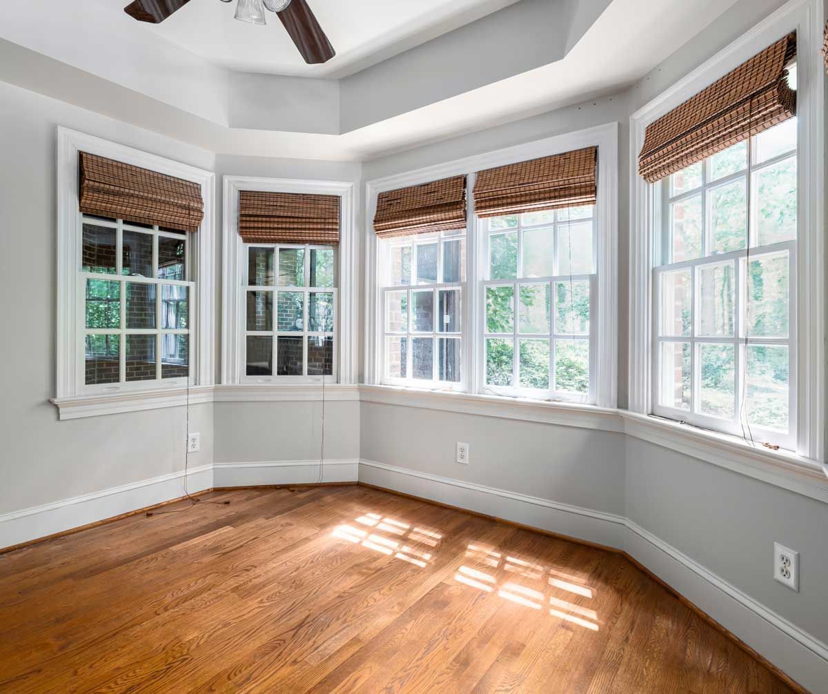 An empty room with a lot of windows and a ceiling fan.