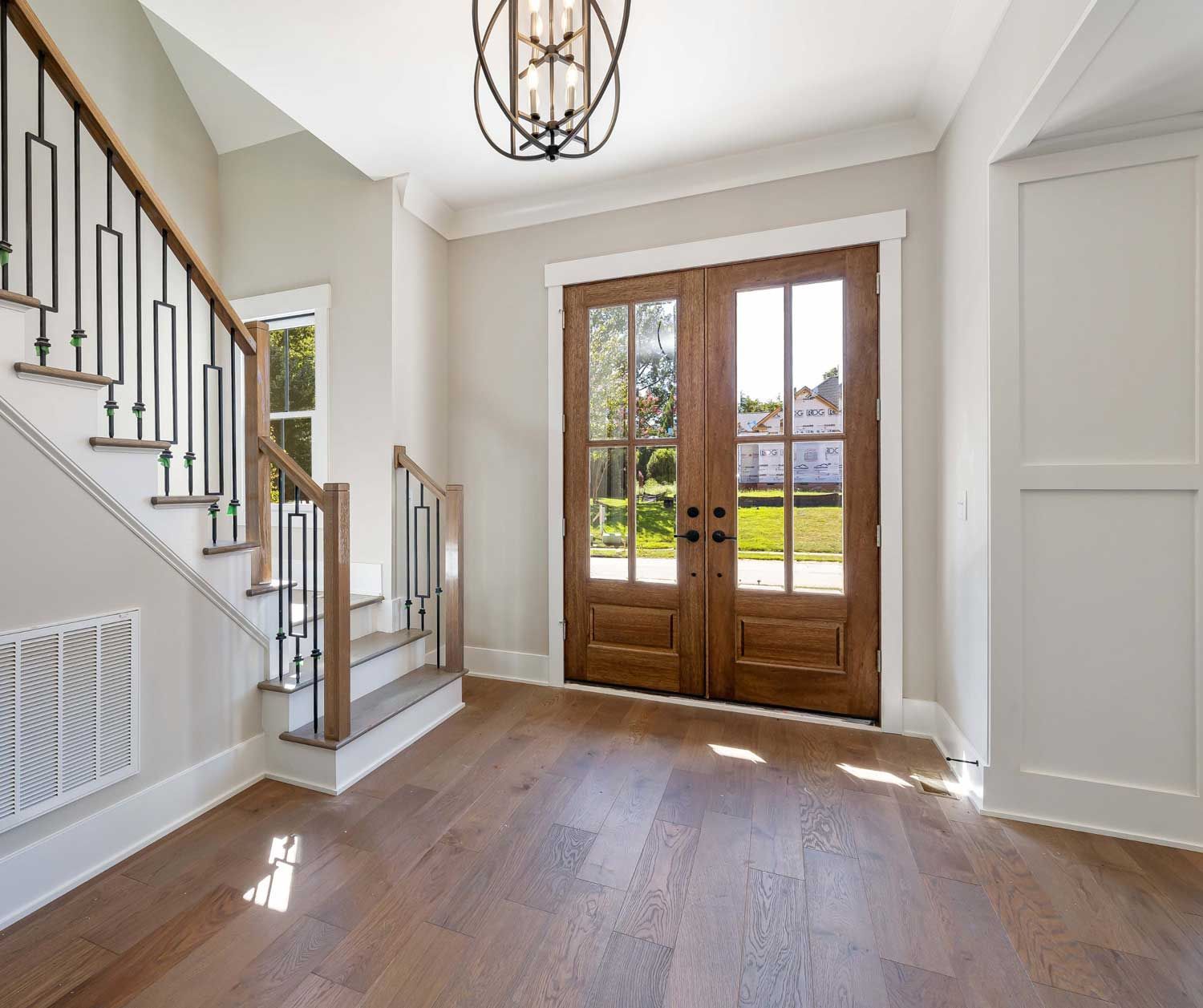 A hallway with hardwood floors and stairs in a house.