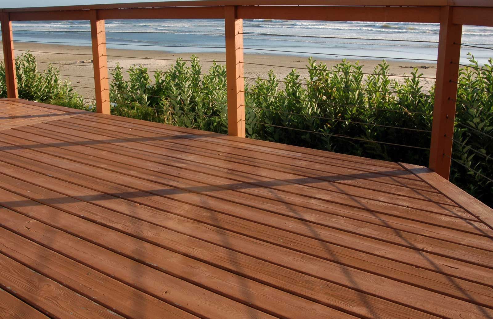 A wooden deck with a railing overlooking the beach