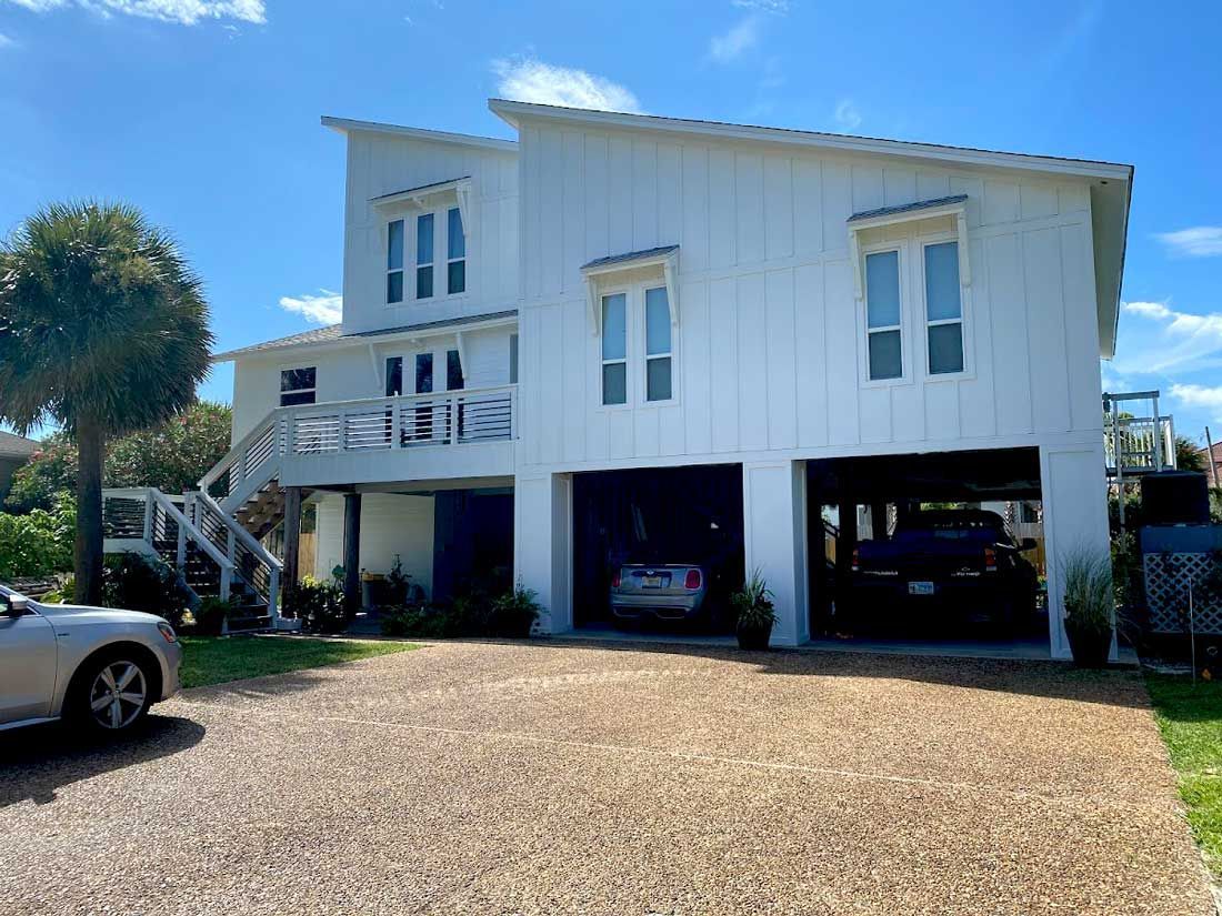 A large white house with a car parked in front of it.