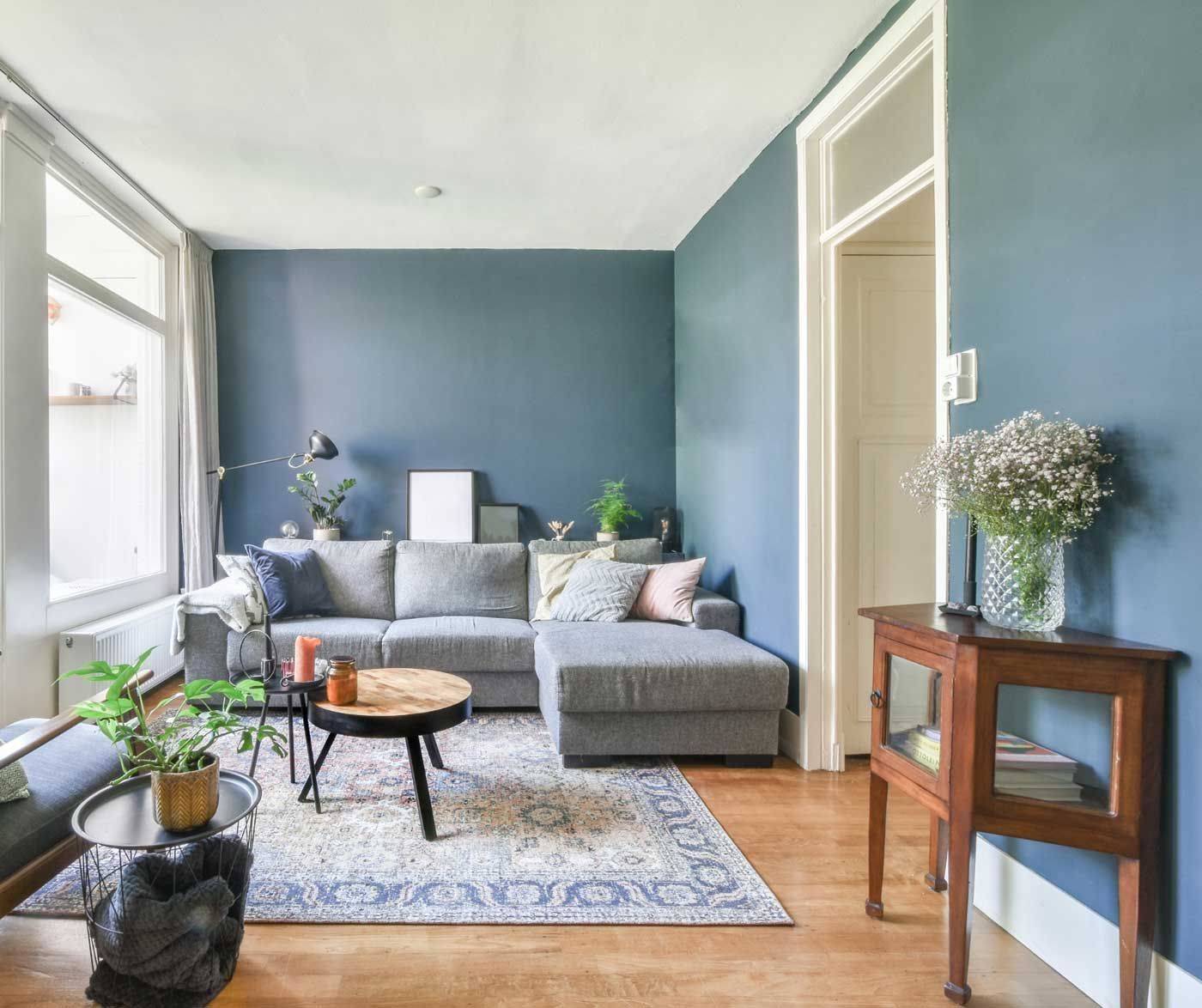 A living room with blue walls , a couch , a table , and a rug.