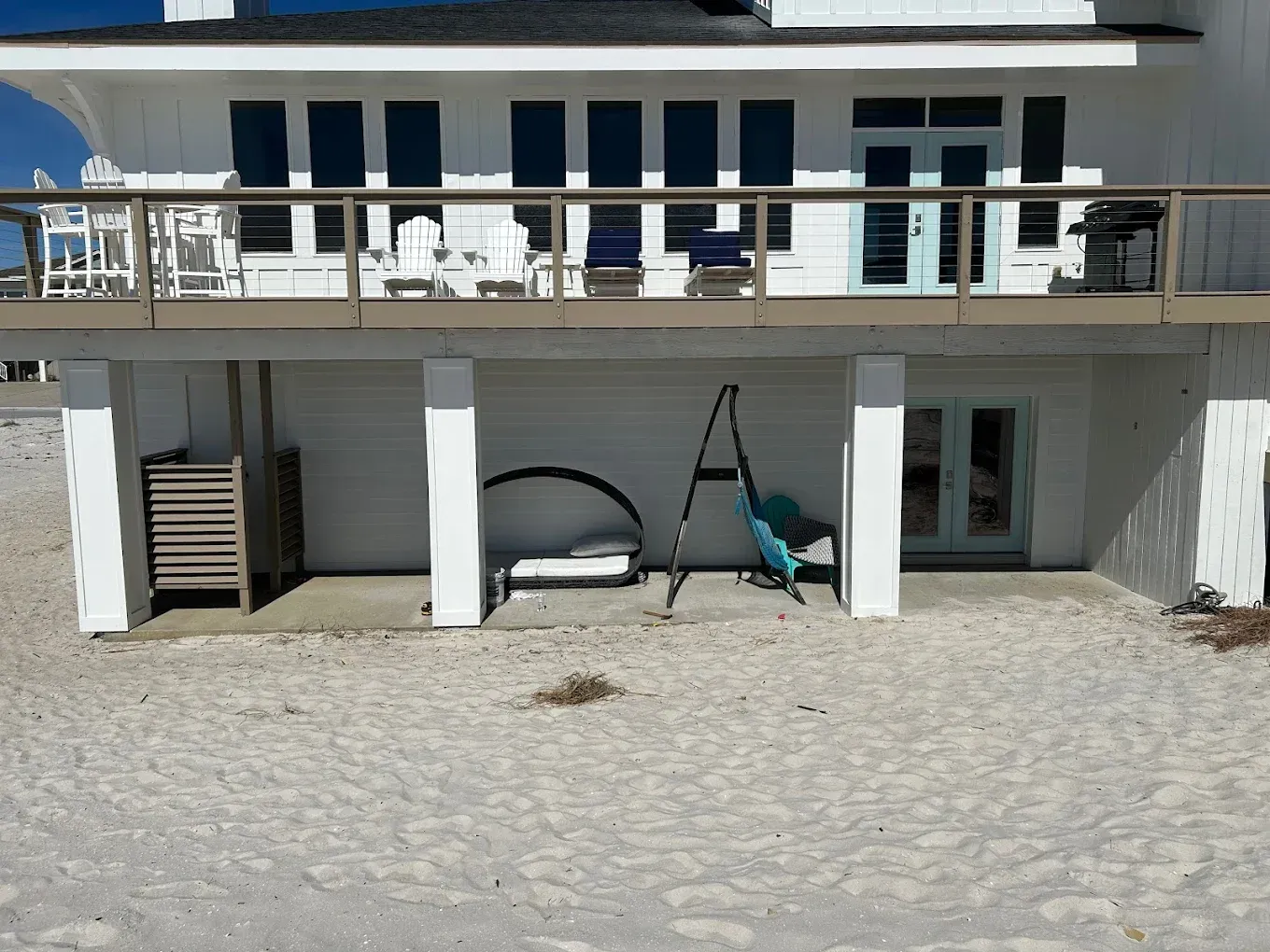 A large white house sits on a sandy beach