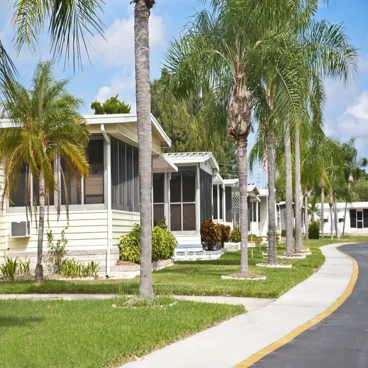 A row of mobile homes with screened in porches and palm trees