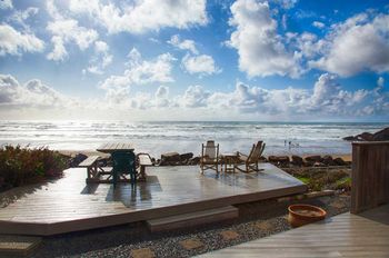 A wooden deck with chairs and a table overlooking the ocean.