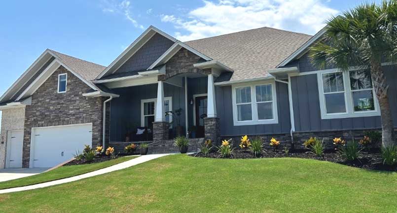 A large house with a lot of windows is sitting on top of a lush green hill.